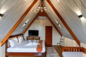 a attic bedroom with a bed and a tv at Paragos Silvina's Cabin 2 Resort Hotel in Maitim