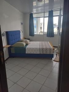 a bedroom with a blue bed and a window at SWEET - City center room Papeete in Papeete