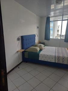 a bedroom with a bed with a blue head board at SWEET - City center room Papeete in Papeete