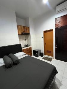 a bedroom with a large bed and a kitchen at Santru home in Denpasar