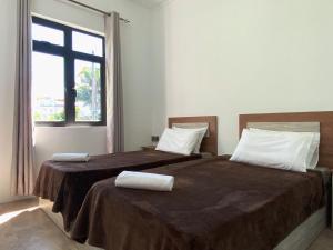 two beds in a room with a window at Villa Oleemun Rezabeen - Mont Choisy in Mont Choisy