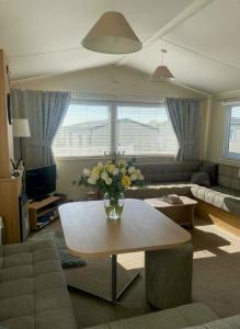 a living room with a vase of flowers on a table at Seashells - Exclusive Private Area to Side in Coldingham
