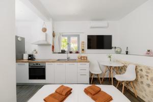 a kitchen with white cabinets and a table and chairs at Lithos Blue Agios Vasilios in Áyios Vasílios
