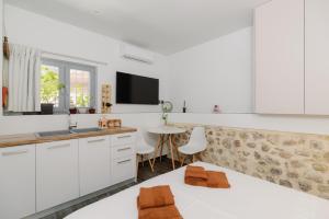 a kitchen with white cabinets and a sink and a table at Lithos Blue Agios Vasilios in Áyios Vasílios