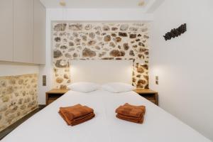 a bedroom with a white bed with two pillows on it at Lithos Blue Agios Vasilios in Áyios Vasílios