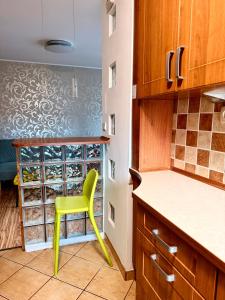 a yellow chair in a kitchen with a wine rack at Robotnicza 59 Old Town Apartment in Elblag