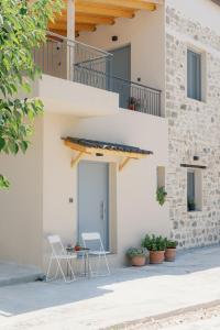 two chairs and a table in front of a building at Lithos Blue Agios Vasilios in Áyios Vasílios