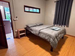 a small bedroom with a bed and a window at Honey Home Pai in Pai