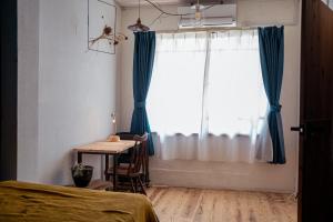 a bedroom with a table and a window with blue curtains at 暮らす実験室 in Taketa +16 photos