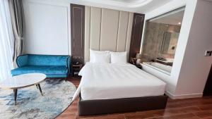 a hotel room with a bed and a blue couch at Khác Sạn Oytes Bay in Xa Thang Nhi