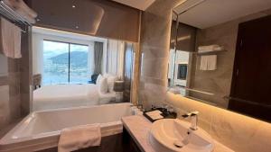 a bathroom with a tub and a sink and a bed at Khác Sạn Oytes Bay in Xa Thang Nhi