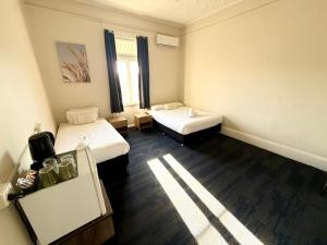 a small room with two beds and a window at Imperial Hotel Singleton in Singleton