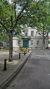 a large white building with a green door on a street at Appartement centre ville- cour- pkg proximité in Aurillac