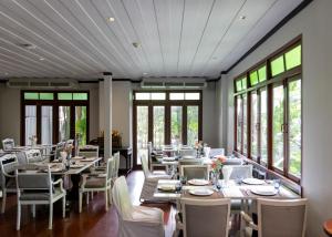 a dining room with tables and chairs and windows at The Raweekanlaya Bangkok Wellness Cuisine Resort in Bangkok