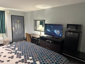 a hotel room with a bed and a desk with a television at Western Motel - Jesup in Jesup