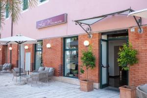 a brick building with tables and chairs and an umbrella at Hotel Miramare in Pietra Ligure