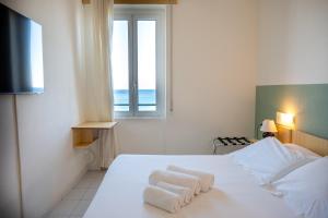 a white bedroom with a bed with towels on it at Hotel Miramare in Pietra Ligure
