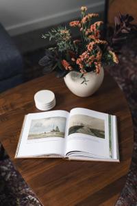 Ein offenes Buch auf einem Tisch mit einer Vase voller Blumen in der Unterkunft The Brickworks at the 1896 Building in Kaslo