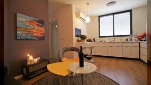 a living room with a table and a kitchen at Cozy modern apartment in Hadera in H̱adera