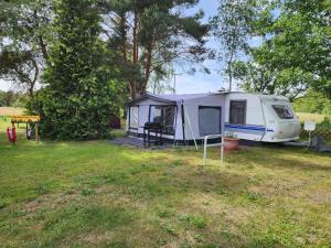 a tent parked in a field next to trees at Wohnwagen Nele in Schwarzbach +3 photos