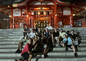 a group of people sitting on steps in front of a temple at UNPLAN Shinjuku in Tokyo