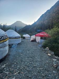 a group of tents on a rocky ground with mountains at Kerben yurt camp in Mineralʼnyy Istochnik Altyn-Arasan
