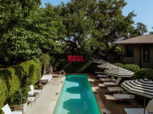 a swimming pool with lounge chairs and umbrellas and a sign that reads soul at Hotel Saint Cecilia in Austin