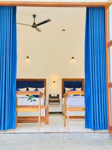 two beds in a room with blue curtains at Nilwadula Hotel Udawalawe in Ratkarawwa