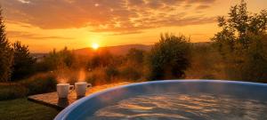 a hot tub with a sunset in the background at Bellevue Beam House in Covasna