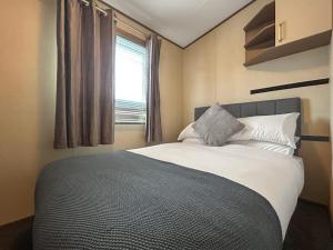 a bedroom with a large bed with a window at The Fern caravan 17 in Angus +2 photos