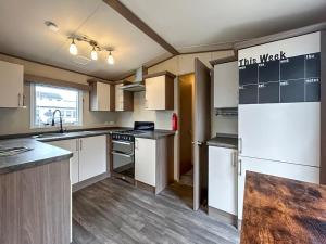 a kitchen with white cabinets and a refrigerator at The Fern caravan 17 in Angus