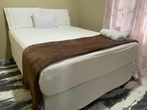 a bed with white sheets and a brown blanket at hotel harmony in El Edén