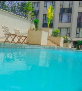 a swimming pool with two chairs and a building at Bellora Urban Homes in Ongata Rongai  +2 photos