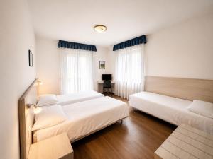 a room with three beds and a desk in it at Hotel International in Tarvisio