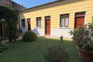 a yellow house with two doors and a yard at Il Giardinetto Rooms in Ferrara