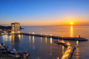 a view of a harbor with a sunset in the water at Ramada by Wyndham Gangwon Sokcho in Sokcho