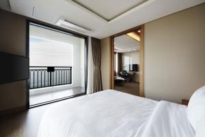 a bedroom with a white bed and a large window at Ramada by Wyndham Gangwon Sokcho in Sokcho