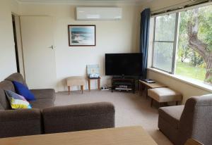 a living room with a couch and a flat screen tv at Beach Break in Tathra