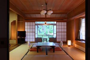 a dining room with a table and chairs and a window at Yudanaka Yumoto in Yamanouchi