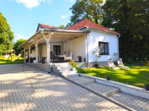 a small white house with a porch and chairs at Búj-Lak Vendégház in Zalaszentmárton
