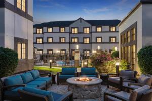 a courtyard with chairs and a fire pit in front of a building at Hyatt House Morristown in Morristown