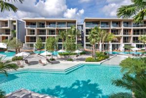 an image of a resort swimming pool with palm trees at Wyndham Grand Nai Harn Beach Phuket in Nai Harn Beach