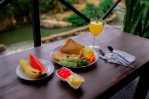 a table with two plates of food and a glass of orange juice at Grounder's River Cabin in Nanu Oya