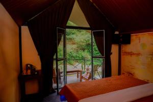 a bedroom with a bed and a large window at Grounder's River Cabin in Nanu Oya