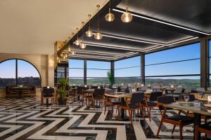 a dining room with tables and chairs and large windows at Ramada Encore by Wyndham Midyat in Midyat