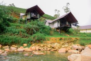 two houses on a hill next to a river at Grounder's River Cabin in Nanu Oya