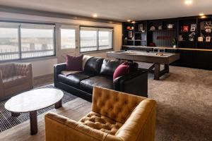 a living room with a leather couch and a pool table at Galt House Hotel, A Trademark Collection Hotel in Louisville