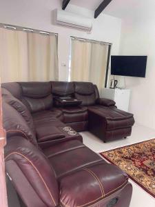 a brown leather couch in a living room with a flat screen tv at Mana Backpacker and Dive Resort in Nadi
