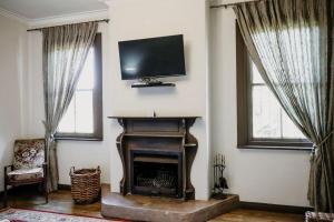 a living room with a fireplace and a flat screen tv at De Mist Graskop in Graskop