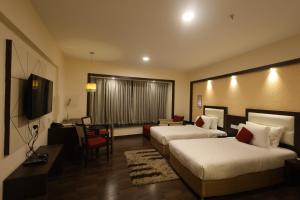 a hotel room with two beds and a desk at Holiday Home Ranchi in Rānchī